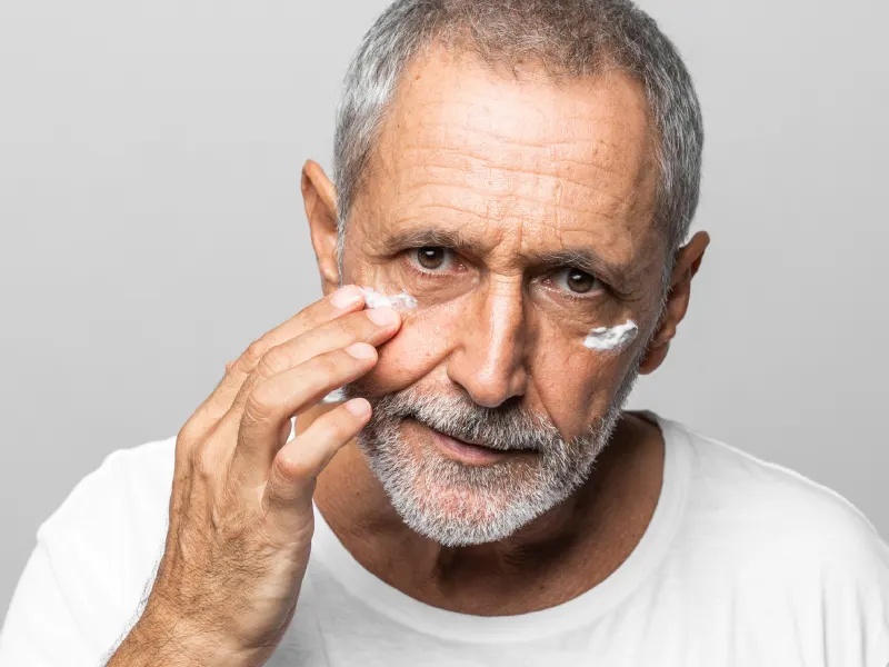 homem a aplicar creme anti pés de galinha