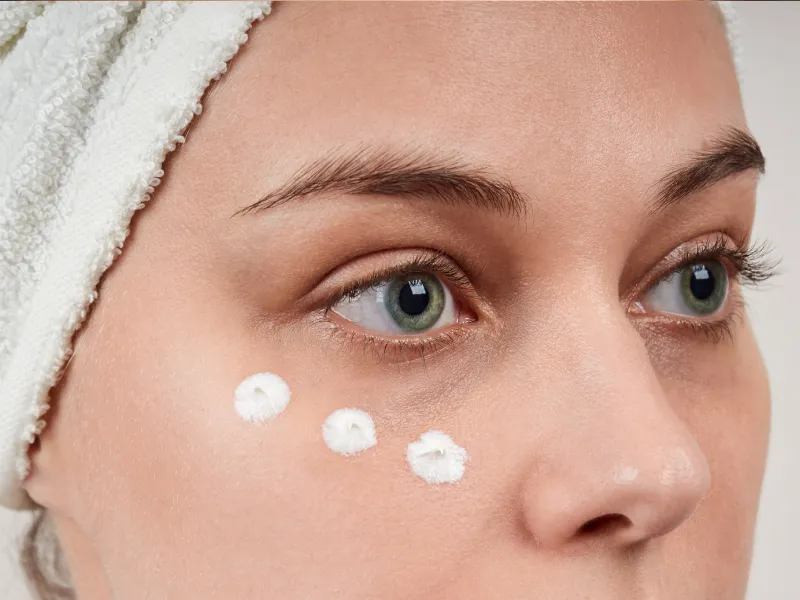 retrato próximo de uma mulher com creme de contorno de olhos aplicado