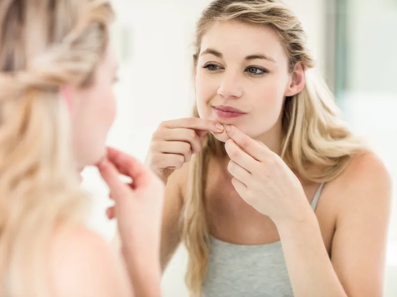 mulher a espremer borbulha em frente ao espelho