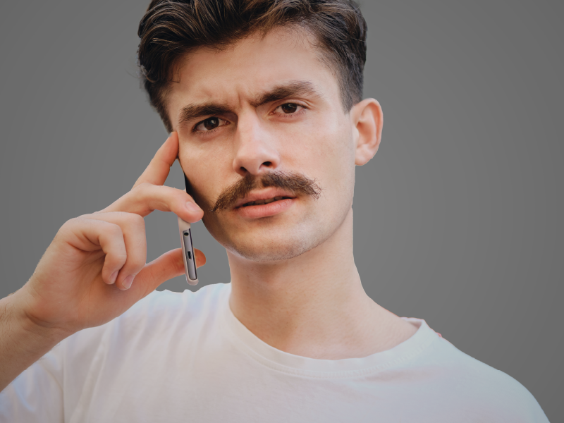 foto de homem a segurar um telemóvel e um bigode clássico