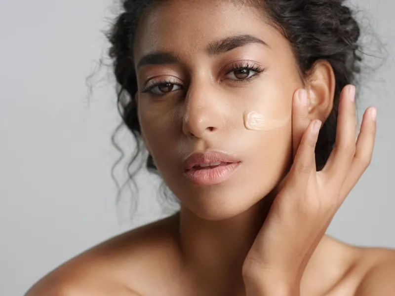 uma mulher com um pouco de BB cream por aplicar no rosto