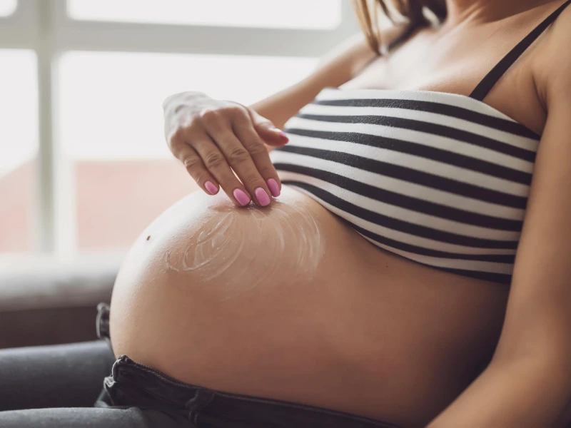 foto próxima de uma mulher a espalhar creme na barriga de grávida