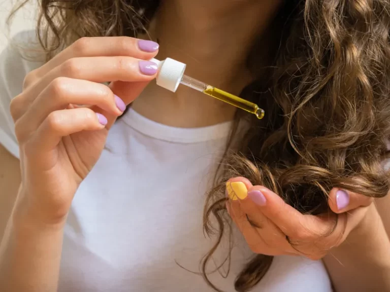 uma foto próxima de uma mulher a aplicar sérum capilar