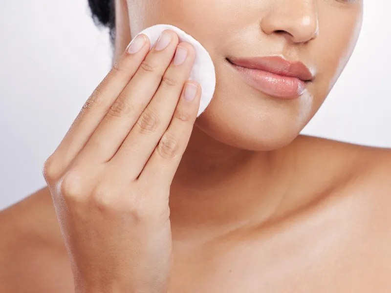 foto próxima de uma mulher com um disco desmaquilhante na mão enquanto se remove maquilhagem