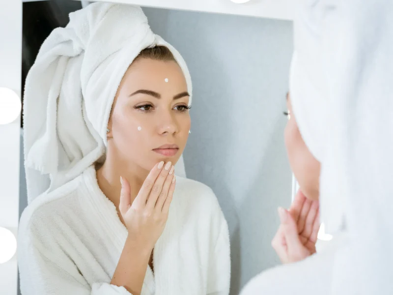 mulher a cuidar da pele em frente ao espelho