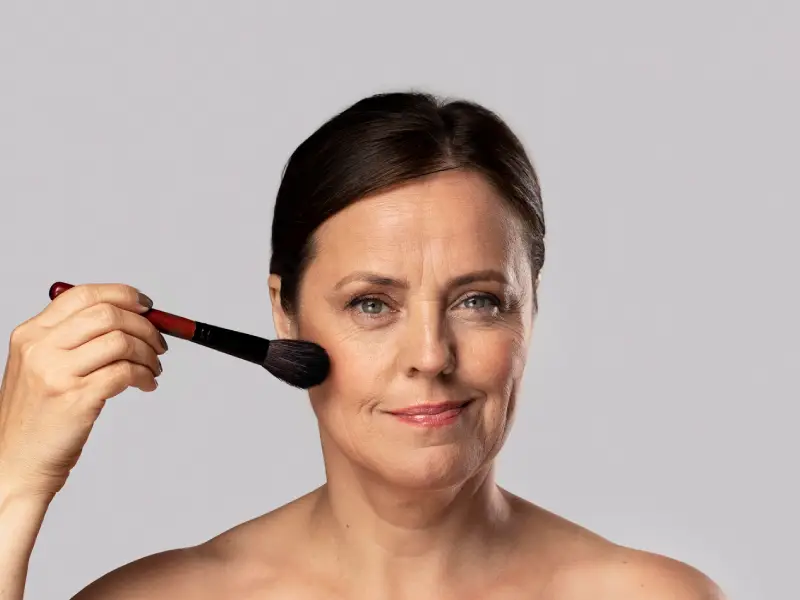 mulher mais envelhecida a aplicar base com pincel