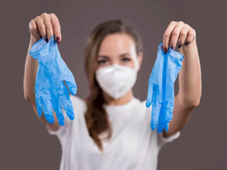 mulher com máscara a segurar luvas de latex