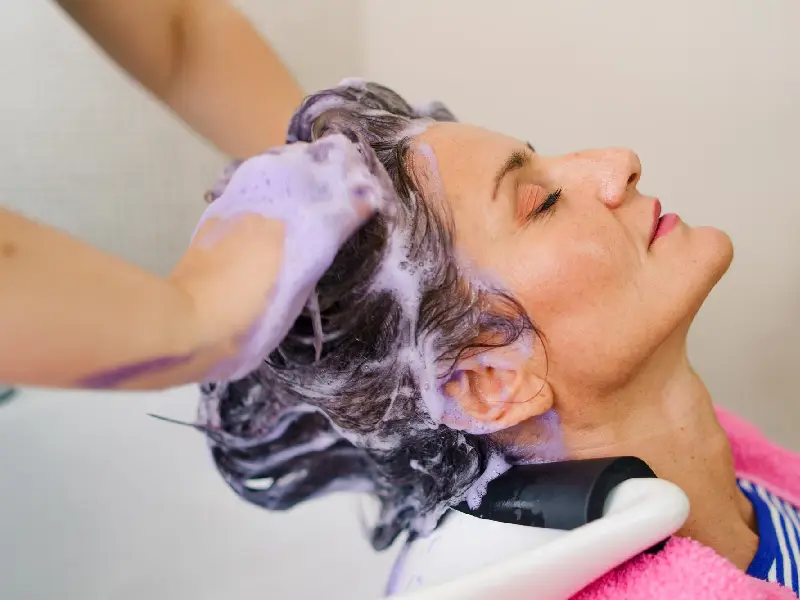 mulher a lavar a cabeça com shampoo roxo