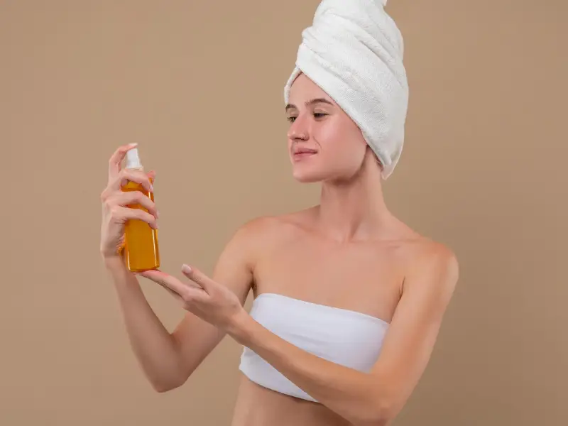 mulher a aplicar óleo hidratante para corpo