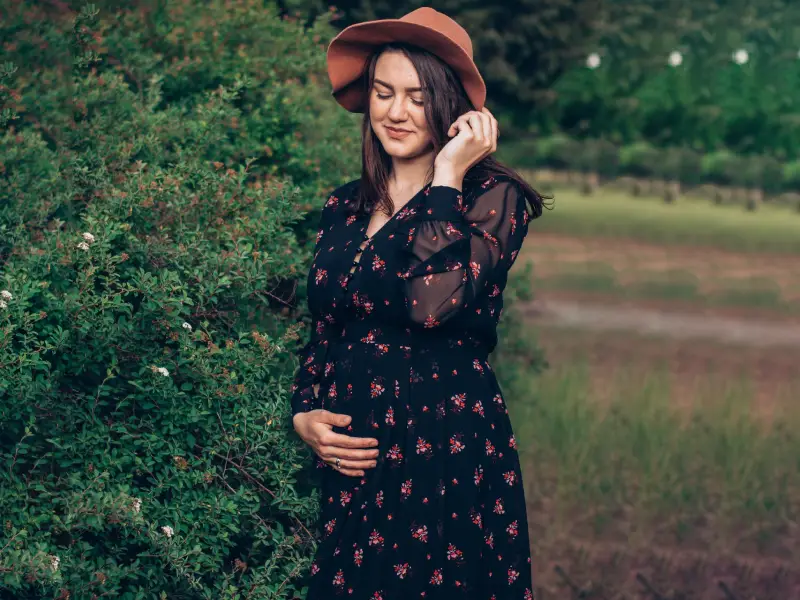 mulher grávida com chapeu de sol e vestido de mangas compridas