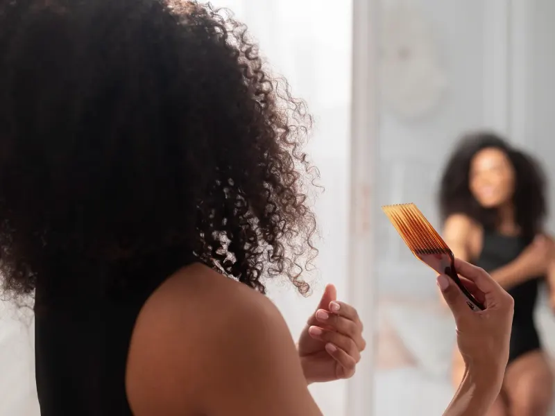 mulher com cabelo crespo a pentear-se